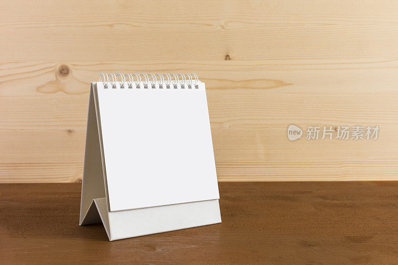 白色空白纸桌上螺旋日历上的木材背景。