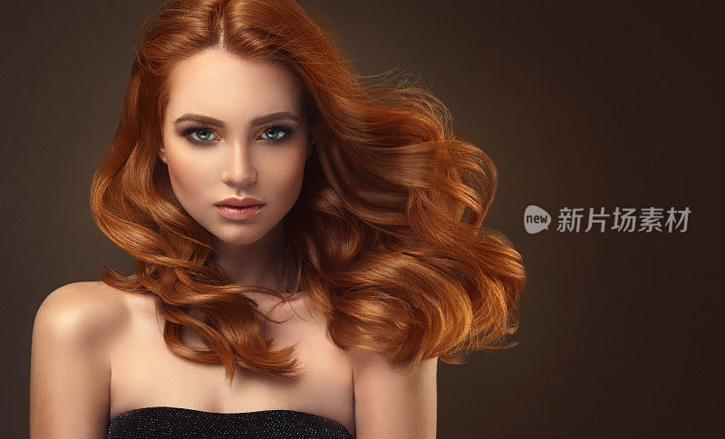 红头发的女人，有着丰满的，有光泽的和卷曲的发型。飞行的头发。