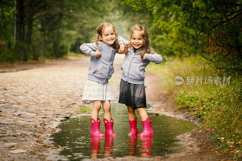 两个可爱的女孩在水坑里玩