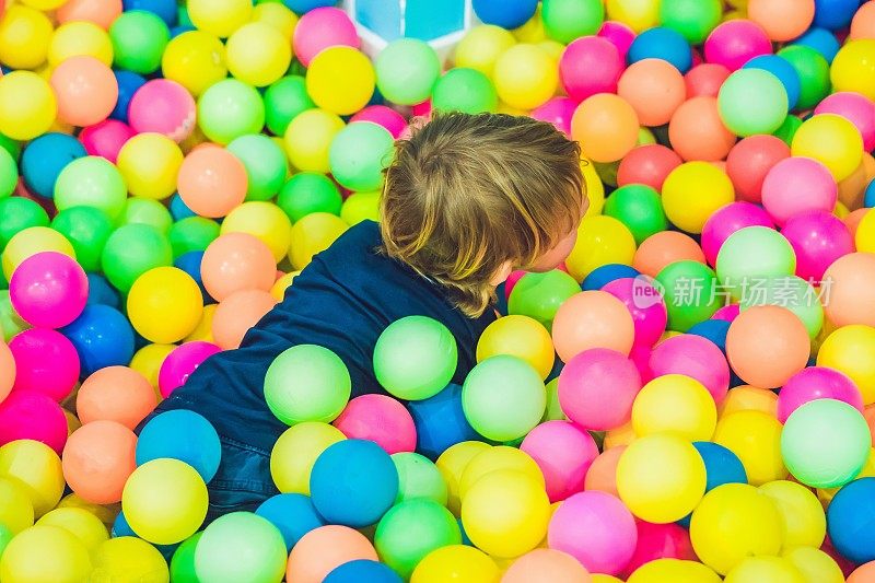快乐的小男孩在操场上玩五颜六色的塑料球。有趣的孩子在室内玩