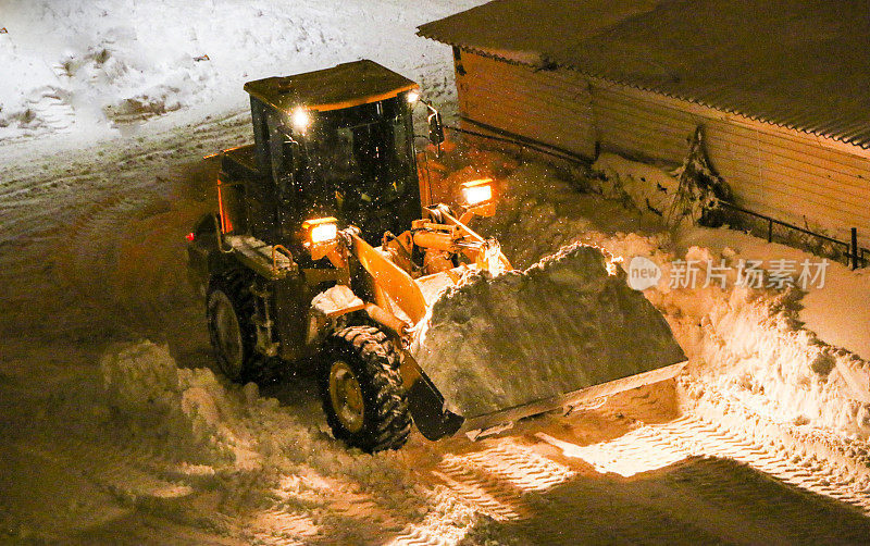 拖拉机清扫积雪。晚上下雪后用推土机清理积雪。晚上大风雪过后，平地员把雪耙成一大堆
