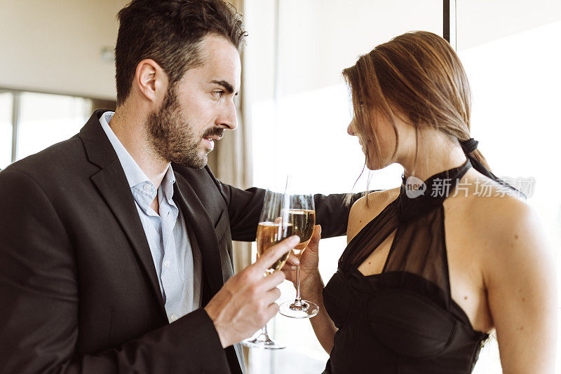 一对优雅的夫妇在酒店房间里喝香槟