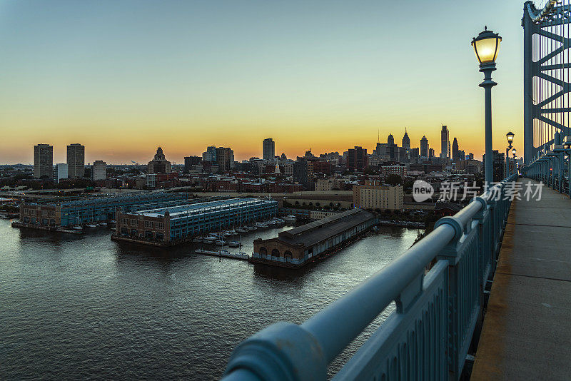 日落时分的费城市中心。从本杰明富兰克林桥上俯瞰老城和德拉瓦河的桥墩。