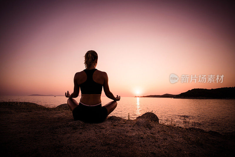 女人在日落时在海滩沉思的背影。