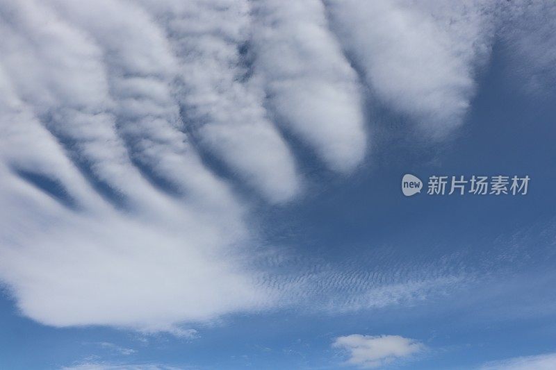 蓝色天空映衬着蓬松、缕缕白云的特写