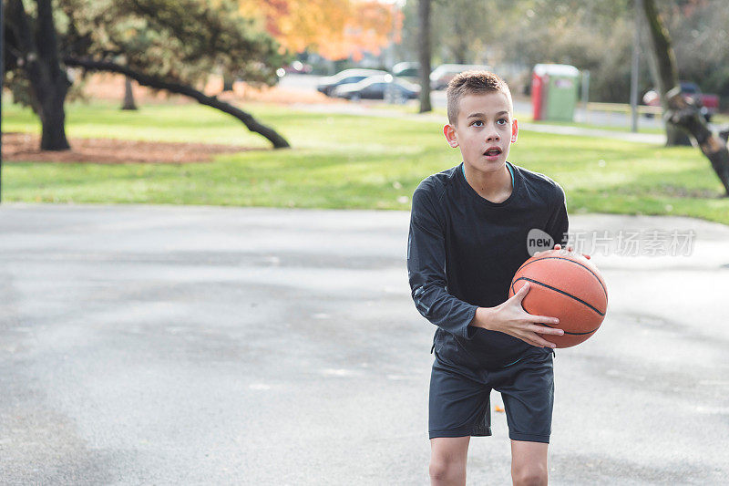 一个小学男孩在篮球场上练习投篮