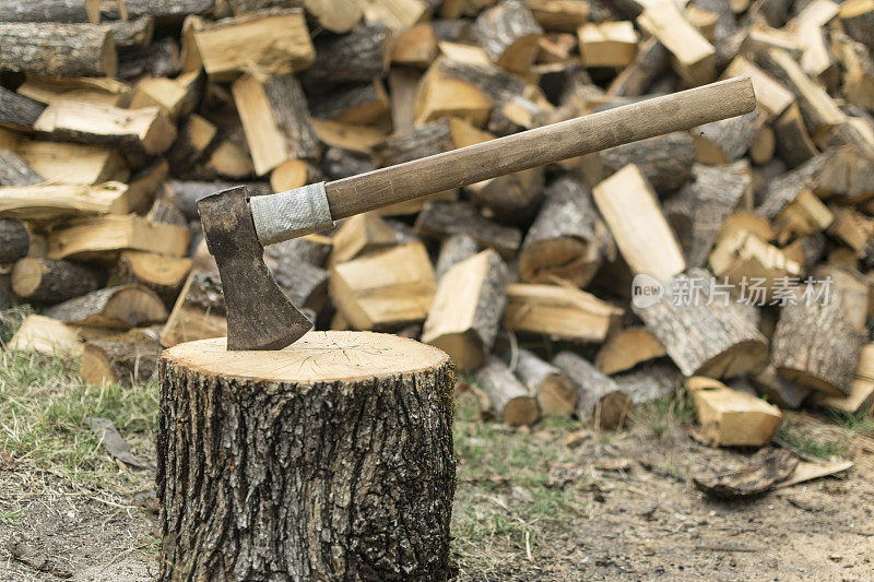 一把斧头卡在一堆木头前面的一根圆木上。