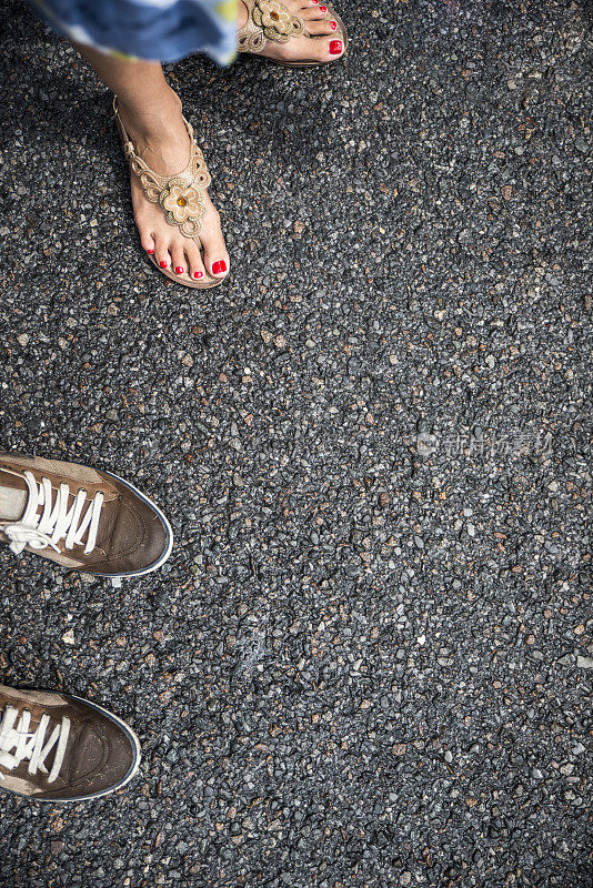 女人和男人的脚踩在潮湿的沥青上