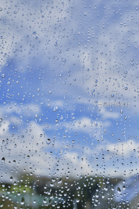 暴风雨过后，透过窗户可以看到蓝天和白云的雨滴。