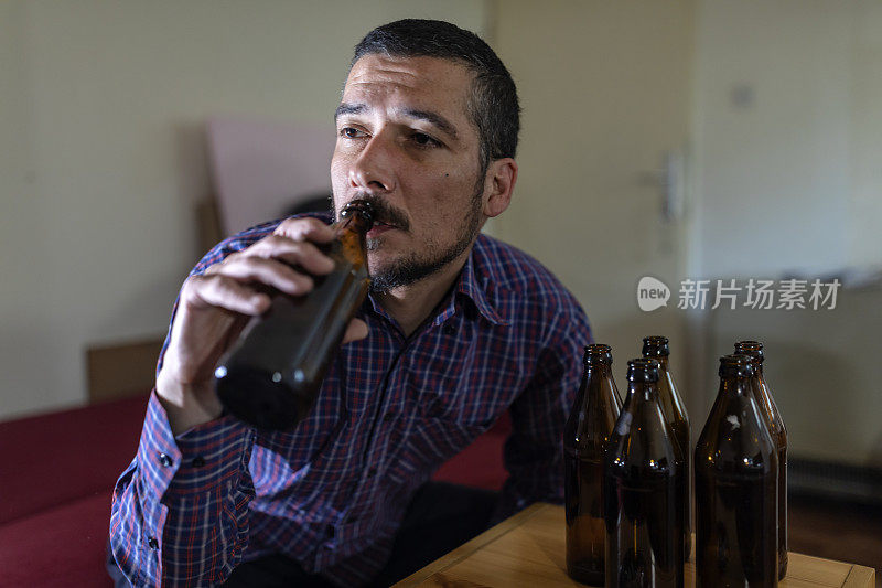 年轻悲伤的醉酒男子喝啤酒和酒精感到浪费，孤独和绝望的痛苦和情绪压力。人与酗酒、上瘾和男人抑郁的概念。