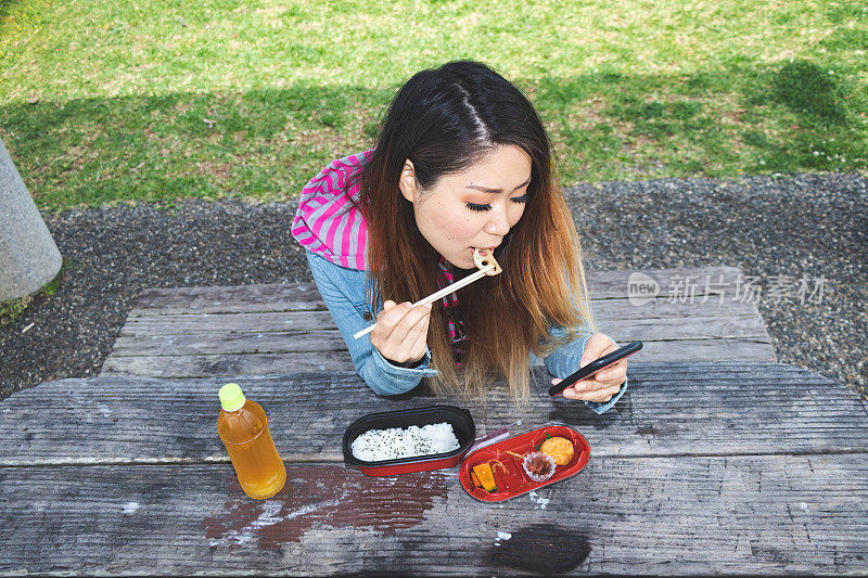 日本女子一边吃便当一边看手机