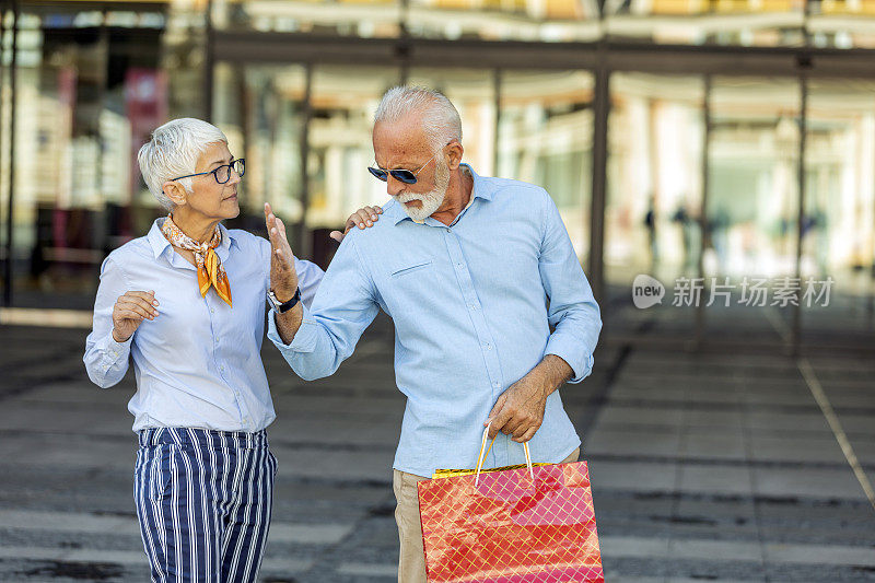 购物失败后，一对成年夫妇在街上拿着纸袋