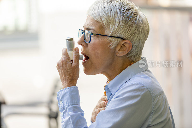 高级商务女性正坐在餐厅里，吸入治疗哮喘的喷雾