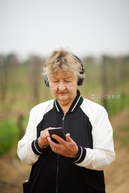 一位老年妇女一边锻炼一边听音乐打字