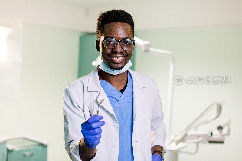 年轻男性非裔美国牙医穿着制服在他的工作地点牙科诊所