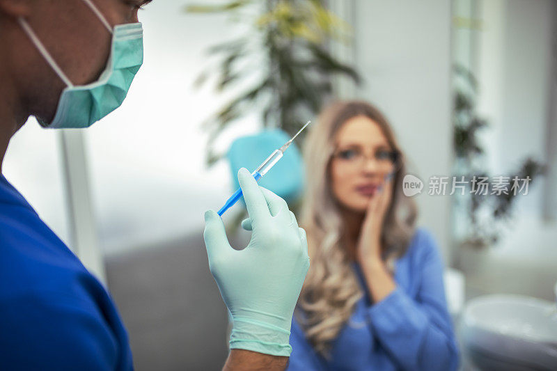 牙医拿着注射器。女人害怕注射的概念