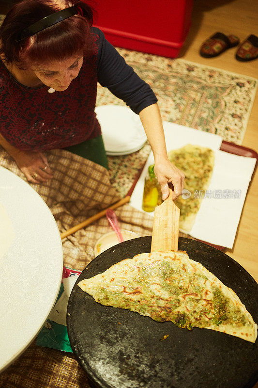 一个女人正在客厅里用电子设备做馅饼