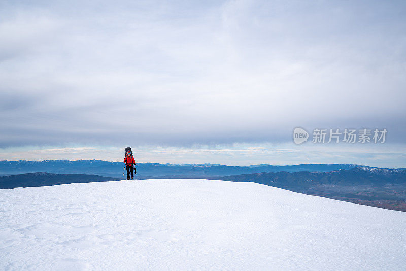 女性登山者在冬天行走在这座高海拔的山峰上