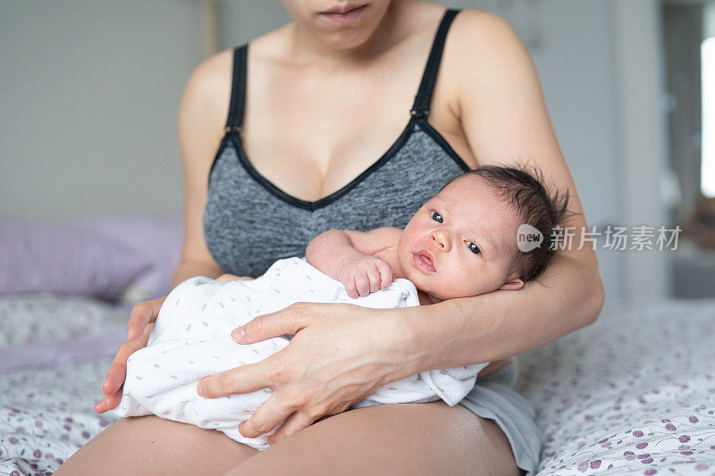 美丽的混血年轻母亲抱着新生的女儿