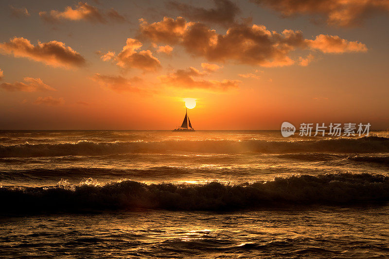 剪影的帆船漂浮在夕阳下的橙色海景上