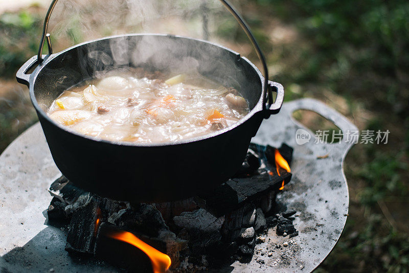 野外露营时在篝火上准备食物，野营旅行时在篝火上烹饪食物。野营厨房，在森林里烧食物。煎锅着火了。露营生活的概念。
