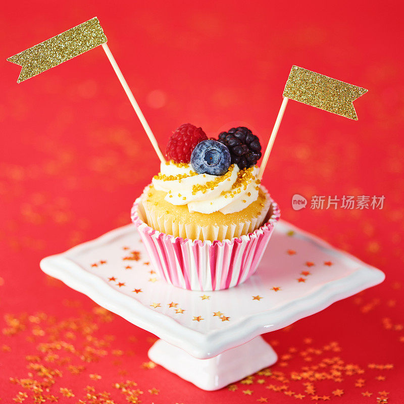 红色背景上有五彩纸屑的庆祝纸杯蛋糕
