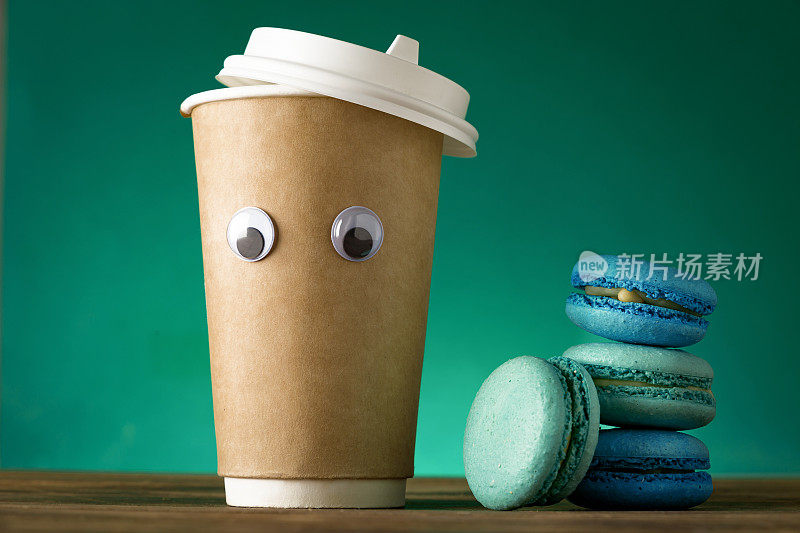 有创意的咖啡杯，绿色背景上有有趣的眼睛和杏仁饼干