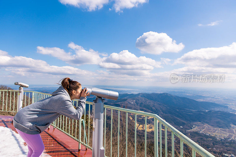 年轻女子用双筒望远镜看风景