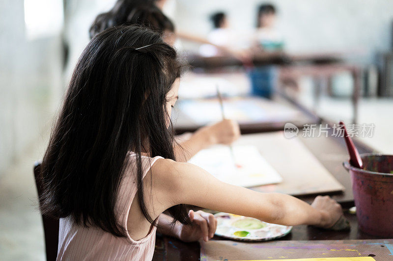 一群亚洲儿童学生在艺术教室，绘画和自信在学校。