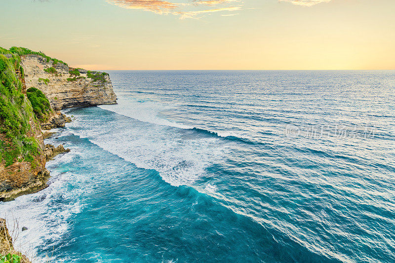 Uluwatu巴厘岛。蓝色的海洋和岩石山，覆盖着热带树木。