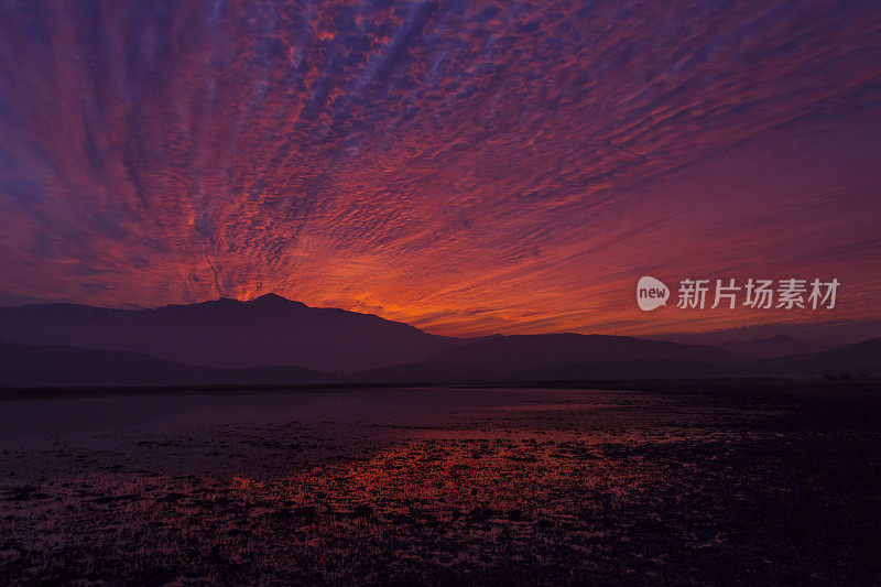 美丽的巴塔哥尼亚风景安第斯山脉与高山与发光的山峰，石头在山湖，反射，橙色红色的天空在日落