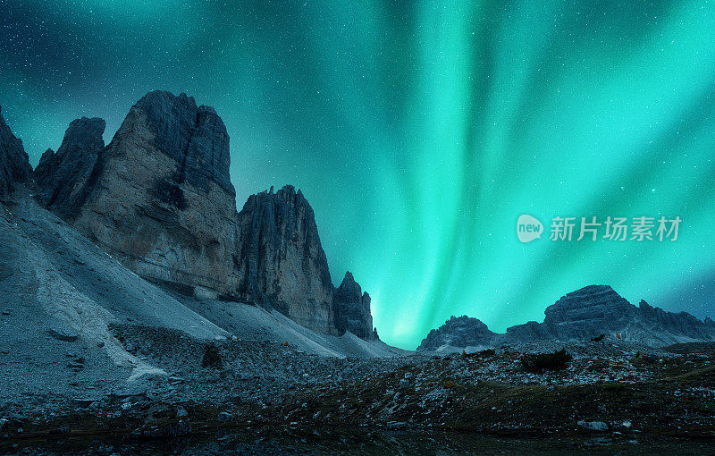 在欧洲，北极光在夜间出现在群山之上。北极光。星空，极地的光和高高的岩石。美丽的风景与绿色极光，山脉，小径，石头。旅行