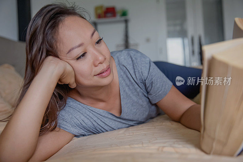 一个中国女人在她的卧室里读一本厚厚的小说