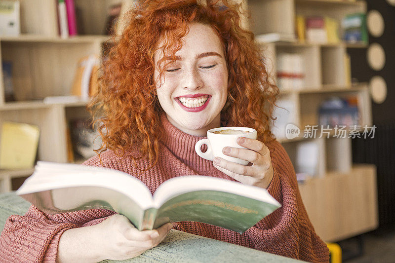 一个女人坐在沙发上，拿着一杯咖啡在书店里看书