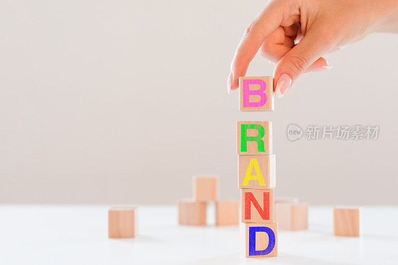 手放印有“BRAND”字样的木方块