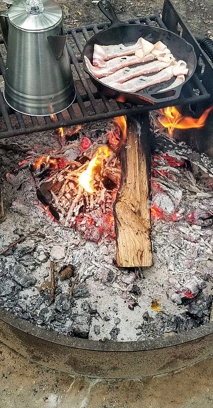 在早晨的篝火上为早餐煮咖啡和培根