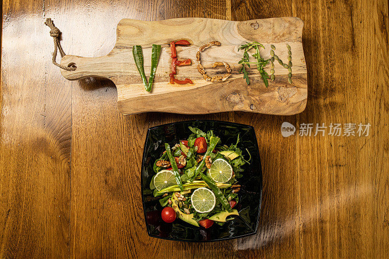 用沙拉碗和蔬菜一起写在切菜板上的素食字