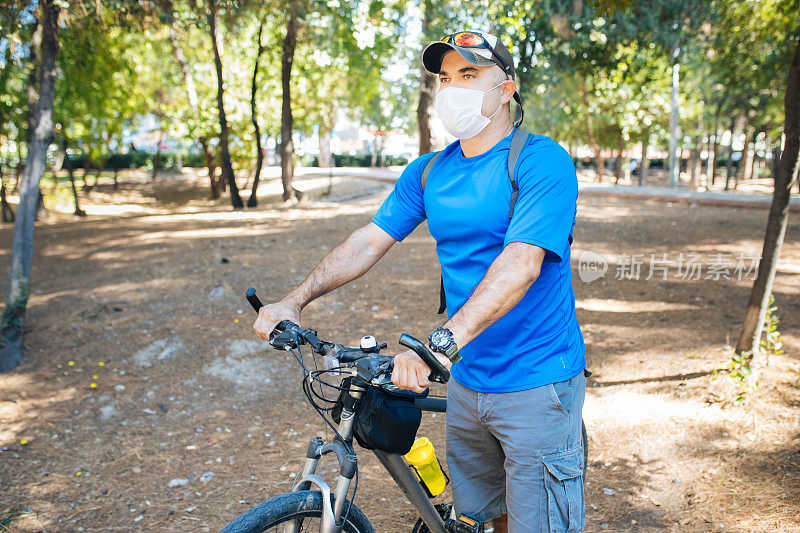 成年男子戴口罩以保持健康，并在周日骑自行车