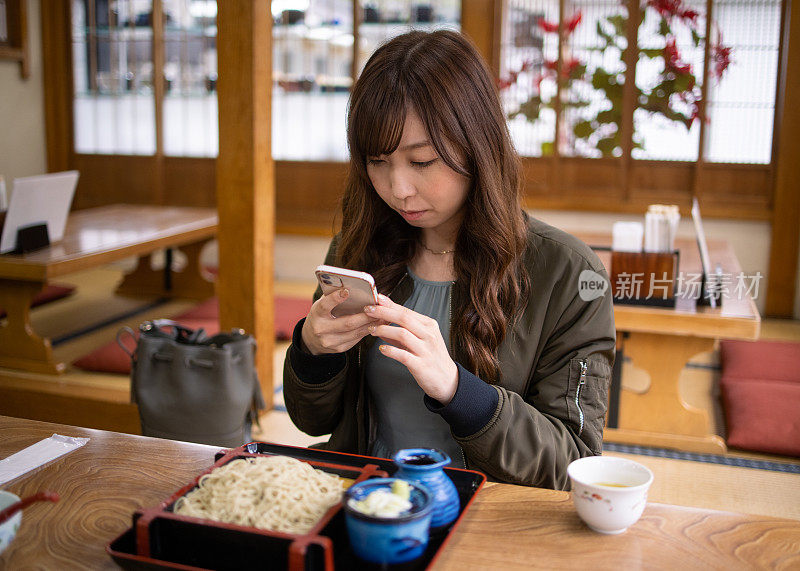 一名年轻女子在日本餐馆拍荞麦面