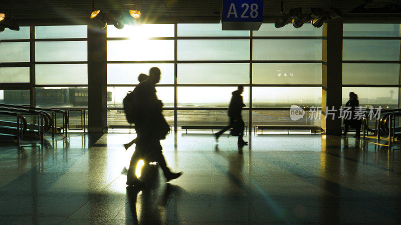 剪影:日出时分，一群面目全非的游客匆匆走过机场航站楼。