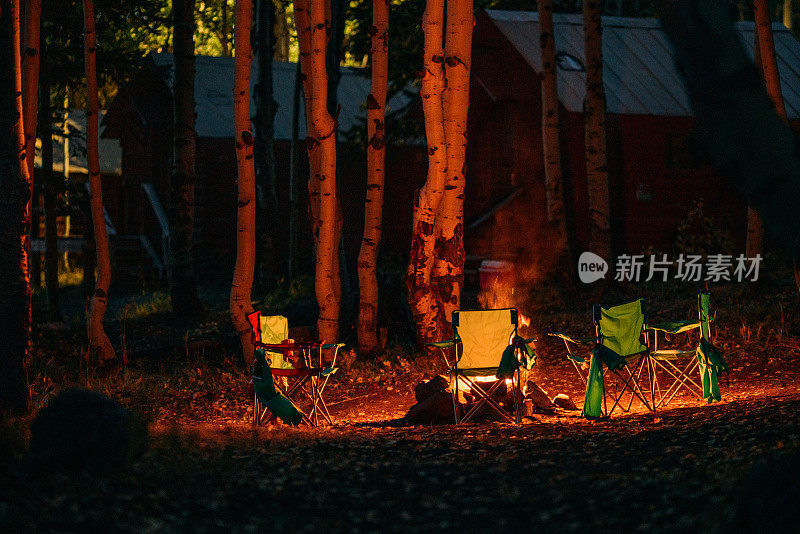 在大梅萨国家森林的梅萨湖旅游度假区的小木屋附近的黄昏，环绕着熊熊篝火的野营椅