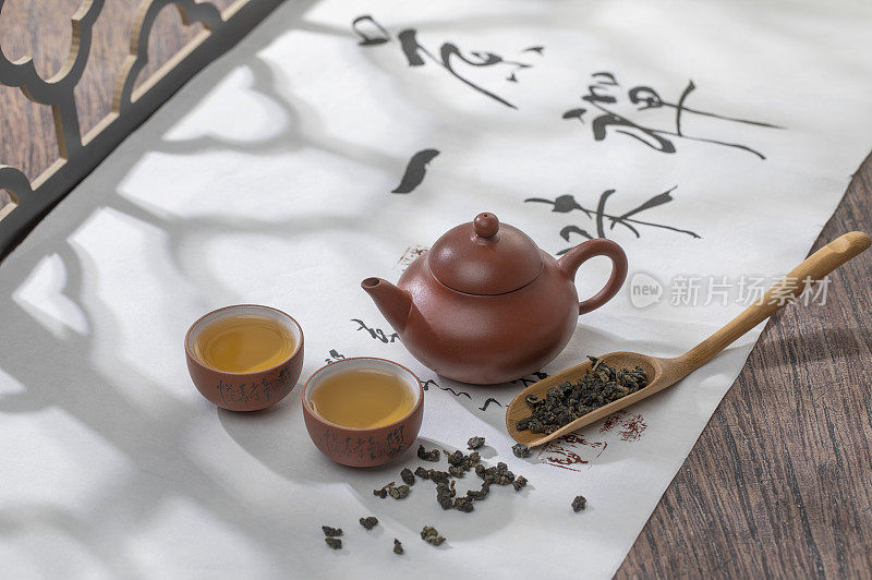 光影下的中国茶壶和茶杯在一幅书法画上富有禅意