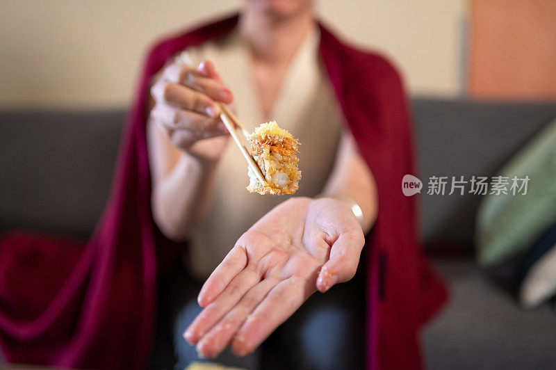 在家吃带酱料的塑料包装寿司卷的妇女