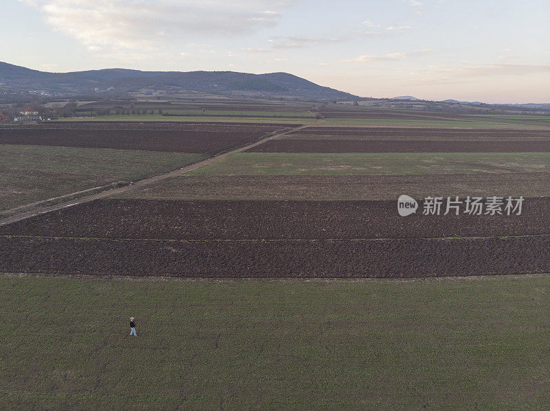 一个成年的农民在他的农场里在早春的时候耕种田地。鸟瞰图。