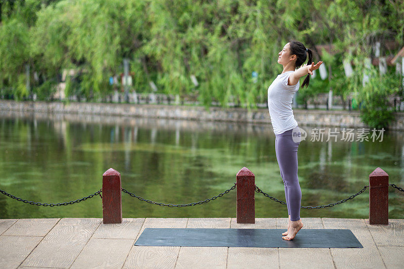 年轻的亚洲妇女在城市公园练习瑜伽