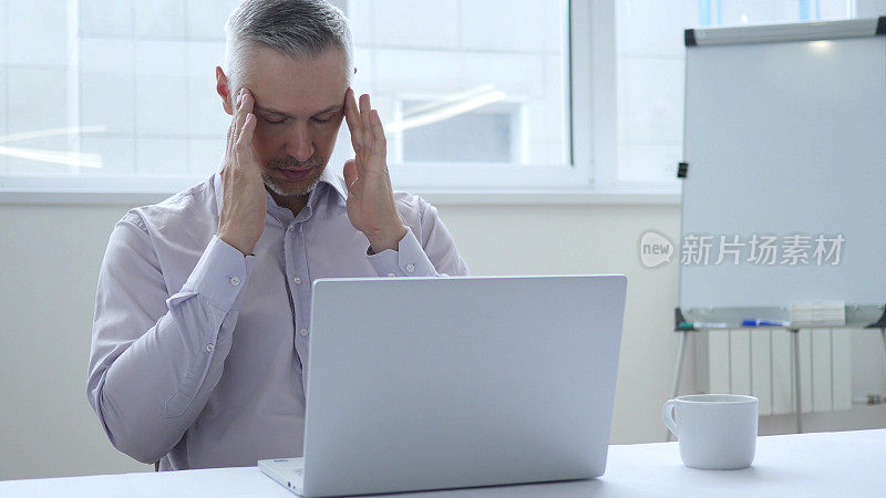 头痛，压力大的商人用笔记本电脑工作
