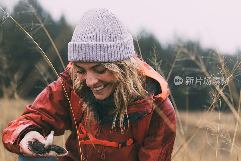 一位美丽的女性大自然爱好者在雨天采摘蘑菇的肖像