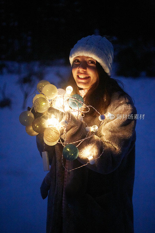 圣诞彩灯女孩看着相机在雪