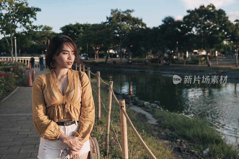 一个孤独和沮丧的亚洲妇女走过公园追忆或思考和分散自己的世俗问题。应对分手或其他麻烦。