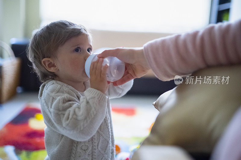 在家随手从婴儿奶瓶给婴儿喝水，拉近距离。